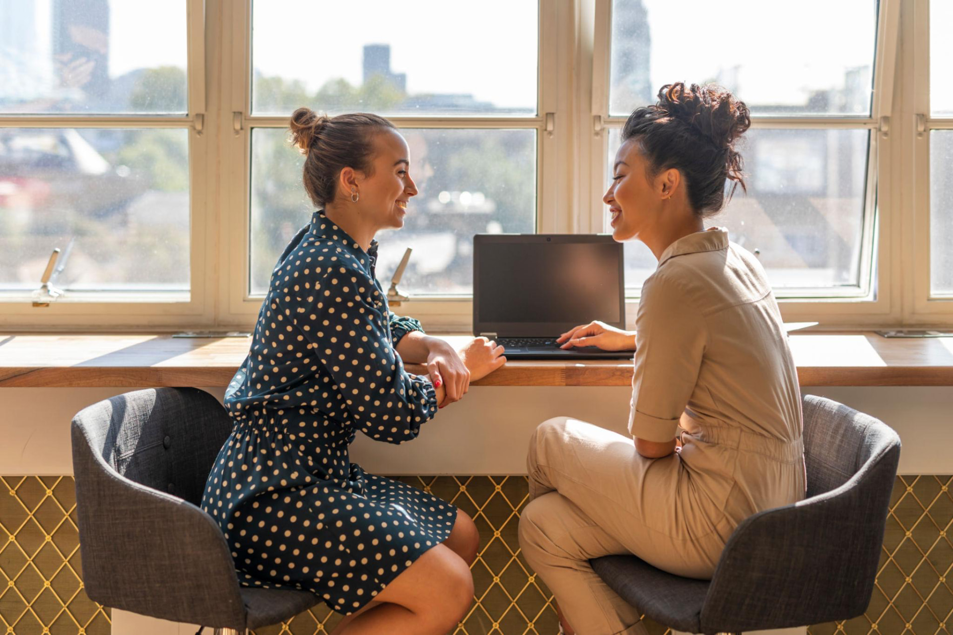 Two colleagues sharing an open conversation beside a window