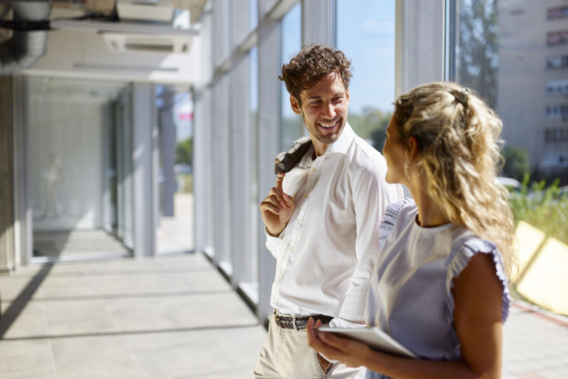 Two colleagues talking while walking through a sunlit workplace